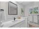 Bathroom featuring white cabinets, black hardware, and a large framed mirror at 3726 E Nichols Ave, Centennial, CO 80122