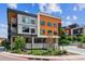 Modern condo building with orange and gray exterior, landscaped grounds, and visible signage, under a partly cloudy sky at 2876 W 53Rd Ave # 305, Denver, CO 80221
