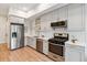 Modern kitchen with stainless steel appliances, white cabinets, subway tile backsplash, and hardwood floors at 2876 W 53Rd Ave # 305, Denver, CO 80221