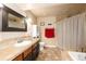 Bathroom with a tile floor, tile countertop sink, dark cabinets, red towel, and neutral-colored walls at 18242 E Bethany Pl, Aurora, CO 80013