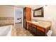 Modern bathroom with a soaking tub, tiled floor, and vanity with a view into the primary bedroom at 18242 E Bethany Pl, Aurora, CO 80013