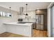 Modern kitchen featuring stainless steel appliances, island with cooktop, and two-tone cabinetry under stylish pendant lights at 1386 Zenobia St, Denver, CO 80204