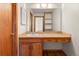 Bathroom with a vanity featuring wood cabinets, drawers, a sink, large mirror, and an open-shelved cabinet at 7681 S Jellison St, Littleton, CO 80127