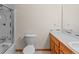 Simple bathroom with white fixtures, wood cabinet, tub and glass door at 7681 S Jellison St, Littleton, CO 80127