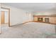 Living room showcasing a fireplace, neutral walls, and large carpeted area with a door leading out at 7681 S Jellison St, Littleton, CO 80127