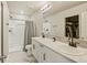 Bright bathroom featuring a dual sink vanity, walk-in shower, and a mirror reflecting a closet with clothes racks at 719 S Hoover Ave, Fort Lupton, CO 80621