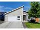 Charming home featuring a modern garage door, gray siding, green lawn, and a beautifully landscaped yard at 719 S Hoover Ave, Fort Lupton, CO 80621