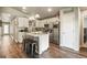 A modern kitchen featuring white cabinets, stainless steel appliances, a center island with bar stools, and wood floors at 719 S Hoover Ave, Fort Lupton, CO 80621
