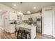 A modern kitchen featuring white cabinets, stainless steel appliances, a center island with bar stools, and wood floors at 719 S Hoover Ave, Fort Lupton, CO 80621