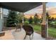 Covered patio features stone pillars, rocking chairs and views of the landscaped yard and sunset at 19067 W 57Th Dr, Golden, CO 80403