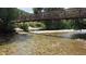 Picturesque bridge over a clear, shallow rocky river surrounded by lush greenery at 19067 W 57Th Dr, Golden, CO 80403