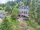 Serene aerial view of a two-story gray home nestled amidst lush greenery and trees, surrounded by a tranquil landscape at 7273 Silverhorn Dr, Evergreen, CO 80439