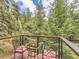Scenic balcony with seating and a table, surrounded by lush greenery and a view of trees at 7273 Silverhorn Dr, Evergreen, CO 80439