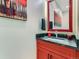 Stylish bathroom featuring a red vanity cabinet with a black granite countertop and decorative mirror at 7273 Silverhorn Dr, Evergreen, CO 80439