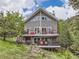 Stunning gray two-story home with a red door and spacious decks surrounded by lush greenery and a beautiful landscape at 7273 Silverhorn Dr, Evergreen, CO 80439