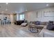 Open-concept living room and kitchen area with hardwood floors and modern furnishings at 2785 Black Hawk Pl, Brighton, CO 80601
