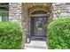 Elegant front door with stone surround and glass accents, nestled amidst lush greenery at 3311 Klondike Pl, Castle Rock, CO 80108