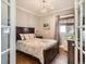 Cozy bedroom with hardwood floors, neutral paint, crown molding, a chandelier and a stylish double bed at 325 S High St, Denver, CO 80209