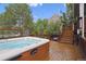 Outdoor hot tub on a wooden deck with steps, surrounded by green trees at 10375 Lions Heart, Lone Tree, CO 80124