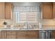 Bright kitchen featuring stainless steel dishwasher, light wood cabinets, and stone countertops at 33 Canongate Ln, Highlands Ranch, CO 80130