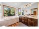 Bathroom featuring a soaking tub and granite-topped double vanity at 7192 Pinewood Dr, Evergreen, CO 80439
