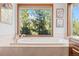 Bright bathroom with a soaking tub overlooking a treed view at 7192 Pinewood Dr, Evergreen, CO 80439
