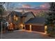 Two-story home featuring a large garage, and inviting curb appeal at dusk at 7192 Pinewood Dr, Evergreen, CO 80439