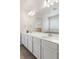 Bathroom featuring dual sinks, large mirror, and white cabinets at 8503 Estes Park Ave, Littleton, CO 80125