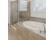 Bathroom featuring a bathtub, glass shower and neutral tile at 8503 Estes Park Ave, Littleton, CO 80125