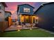 A well-lit backyard with green artificial grass and a wooden deck at dusk at 8974 E 51St Ave, Denver, CO 80238