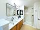 Updated bathroom features double sinks, a large framed mirror, a glass-enclosed shower, and modern fixtures at 12743 W Bowles Pl, Littleton, CO 80127