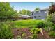 Landscaped backyard features a lush green lawn and beautiful flower gardens surrounding a two-story home at 1672 Maccullen Dr, Erie, CO 80516