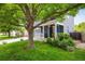 Charming front exterior featuring a blue home, lush lawn, covered porch with seating, and mature shade trees at 1672 Maccullen Dr, Erie, CO 80516