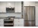 Kitchen features stainless steel refrigerator, microwave, oven, white cabinets, and subway tile backsplash at 1672 Maccullen Dr, Erie, CO 80516