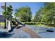 Community playground featuring slides and swings set amongst mature trees and on blue safety flooring at 1672 Maccullen Dr, Erie, CO 80516