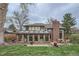 Expansive backyard featuring a sunroom, brick patio, and mature trees at 3633 S Ingalls St, Denver, CO 80235