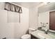 Cozy half bathroom featuring a toilet, sink with countertop, mirror, and window with curtain at 3633 S Ingalls St, Denver, CO 80235