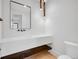 Modern bathroom with floating sink, wood trim, and large mirror and hanging light fixture at 8132 Galileo Way, Littleton, CO 80125