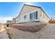 A view of the backyard featuring a modern white home with large glass doors and a retaining wall at 200 Lark Sparrow Way, Bennett, CO 80102