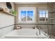 Bright bathroom featuring a soaking tub, picture window with neighborhood view, and a glass-enclosed shower at 14097 Double Dutch Cir, Parker, CO 80134