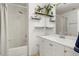 Clean bathroom with white tile, shower/tub combo, and modern vanity with open decorative shelving at 20292 E 47Th Ave, Denver, CO 80249