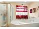 Bright bathroom featuring a glass-enclosed shower, soaking tub, and decorative window treatments at 20292 E 47Th Ave, Denver, CO 80249