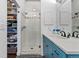 Bathroom featuring blue cabinets, a quartz countertop, glass enclosed shower, and storage at 290 W 12Th Ave # 303, Denver, CO 80204
