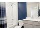 Bright bathroom with a tub-shower combo, white tiles, blue accent wall and gray vanity at 21528 E 59Th Pl, Aurora, CO 80019