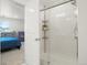 Bathroom featuring a glass walk-in shower with shelving, plus a view into bedroom at 21528 E 59Th Pl, Aurora, CO 80019