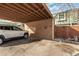 Carport featuring house number 23, a parked car, and a wooden fence at 4950 Homestead Pl # 23, Thornton, CO 80229