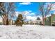 View of townhomes surrounded by mature trees and a large, snow-covered front yard at 4950 Homestead Pl # 23, Thornton, CO 80229
