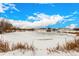Frozen pond featuring surrounding buildings, dry reeds, and a cloudy blue sky at 4950 Homestead Pl # 23, Thornton, CO 80229
