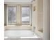 Bright bathroom with a soaking tub, tiled walls, and natural light from large windows at 23561 Genesee Village Road # C, Golden, CO 80401