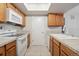 Functional kitchen with white appliances, wood cabinets, ample countertop space, and tile flooring at 23561 Genesee Village Road # C, Golden, CO 80401